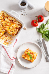 Traditional lasagna made with minced beef bolognese sauce and bechamel sauce topped with basil leaves on light background. Recipe, restaurant menu. Top view