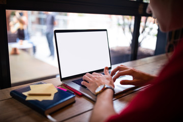 Obraz premium Man professional content writer keyboarding on laptop computer with empty mock up copy space screen background for promotional text message while sitting in coffee shop near window