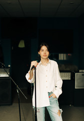 Fototapeta na wymiar Young woman with mic in music studio