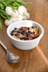Fresh spring oatmeal, quinoa, healthy breakfast on wooden table.