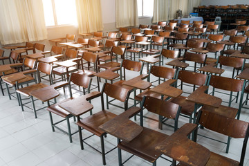 Empty classroom with a lot of chair with no student. Empty classroom with vintage tone wooden chairs. Back to school concept.