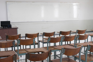 Empty classroom with a lot of chair with no student. Empty classroom with vintage tone wooden chairs. Back to school concept.