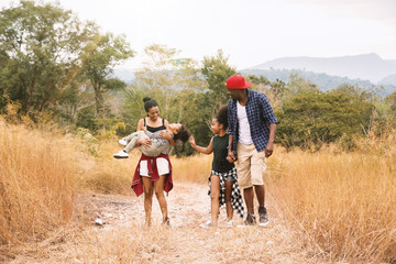 Happy mixed race big family with father, mother holding her daughter and walking on country road. Travel vacation concept