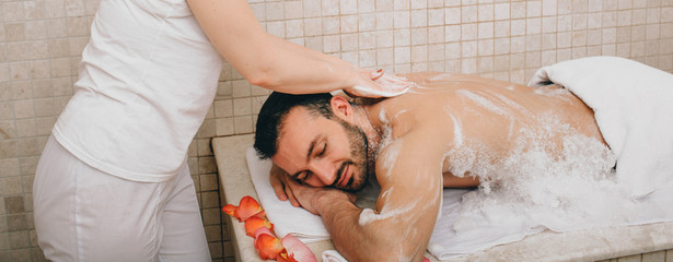 Turkish man enjoying foam massage in a Turkish bath. Hammam worker washes men's skin. Foam massage