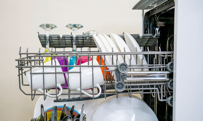 colorful Dishware inside built-in dishwasher. Dishwashing machine rack