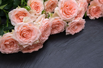 Fresh pink roses on a black background made of natural stone. Copy space