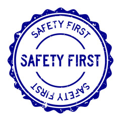 Grunge blue safety first word round rubber seal stamp on white background