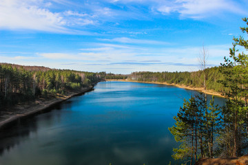 Forest lake panorama on a sunny day. Beautiful turquoise lake surrounded by forest in the nature park of Ogre, Latvia.