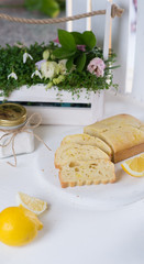 Lemon airy biscuit on a white tray. Table with flowers