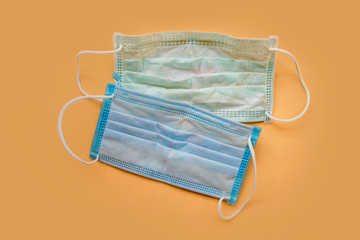 Used green surgical face masks with cosmetic stains, lipstick marks isolated on color background, cause of the spread of germs, virus or bacteria. problem of unhygienic disposal of infectious waste.