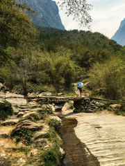Hiker crossing a river on the Annapurna Circuit, in the Himalayas