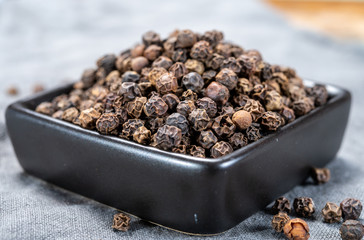 Bowl with dried black round peppers condiment