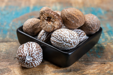 Dried nutmegs nuts in small black bowl