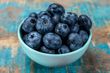 Fresh ripe blueberries in bowl on wooden background