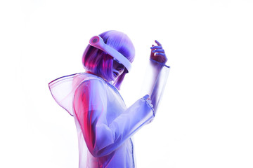 Beautiful woman with purple hair in futuristic costume over white background. Girl in glasses of virtual reality. Augmented reality game, future technology, AI concept. VR. Blue and violet neon light.