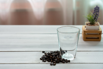 Roasted coffee bean and blank glass on white wooden.