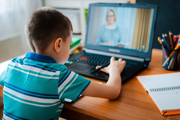 Distance learning online education. A schoolboy boy studies at home and does school homework. A home distance learning