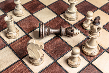 Chess board with black king surrendered to overwhelming force of white chess pieces