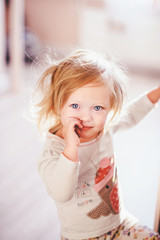 Naklejka premium Cute blonde toddler girl playing with her hands closeup