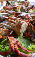 Varied seafood platter varied on the table  (crab, mussels, scallops) decorated with green lettuce, on table with blue paper tablecloth and isolated on white background 