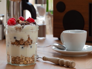 Fresh musli served with yoghurt, fresh raspberries, almonds and chocolate nibs in the jar on the table. Healthy breakfast.