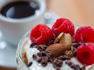 Fresh musli served with yoghurt, fresh raspberries, almonds and chocolate nibs in the jar on the...