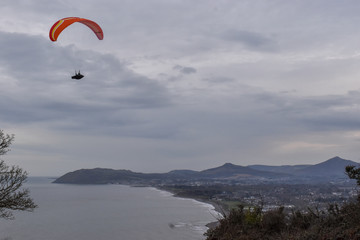 Success concept. A man paragliding in a clear sky on the coast of Ireland