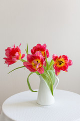 Fresh red tulip flowers bouquet in a white vase on the table. Copy space. Greeting card, happy birthday, mother's day, easter, spring gift