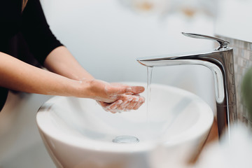 beautiful woman carefully washing hands with soap and sanitiser in home bathroom
