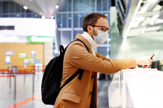 Man in mask at empty airport at check in in coronavirus quarantine isolation, waiting for departure, flight cancellation, pandemic infection worldwide spread, travel restrictions and border shutdown