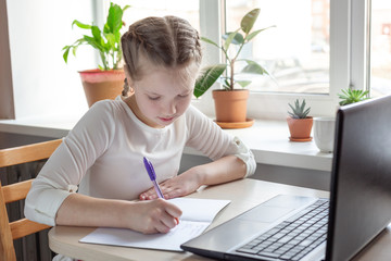 Schoolgirl studying at home using laptop. Home school, online education, home education, quarantine concept