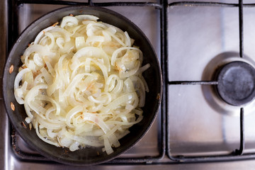 Cooking onions in a frying pan. Home kitchen. Top view. 