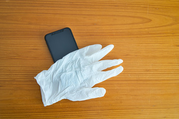 Hand protected by white latex gloves to use of the smartphone as protection against the Covid-19. Coronaviruses, viruses and contagious diseases. Protect yourself when you use your device.