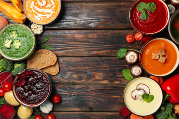 Vegetable soups and ingredients on wooden background, top view
