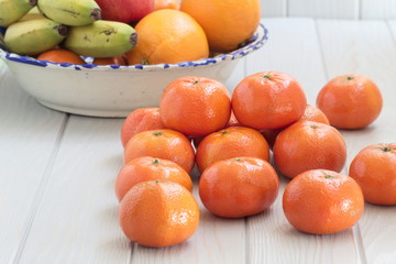 Delicious and juicy tangerines pyramid on spring wooden table with fruit bowl in the background