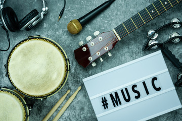 Table top view of music instrument tools concept background.Flat lay of sign to sing for musician or party equipment.Headphone and guitar with set on modern grey cement.space for creative design.