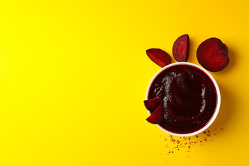 Beet cream soup on yellow background, top view