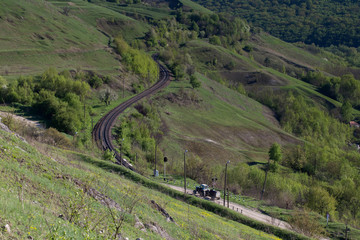The railway passes between the green hills.
