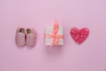 Top view aerial image of decoration Happy mothers day holiday background concept.Flat lay gift box with baby shoes and love shape on modern beautiful pink paper at home office desk.pastel tone.