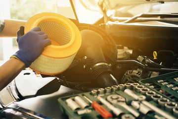 Cropped image of handsome young auto mechanic in uniform repairing car Change car air filter in auto service.selective focus. - obrazy, fototapety, plakaty