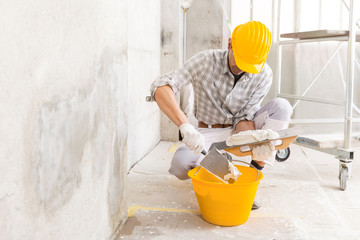 Plasterer loading new plaster from a bucket