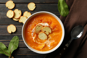 Pumpkin cream soup with croutons on wooden background, top view