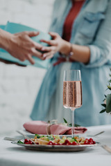 Glass of champagne and couple with present on the background. Soft focus. St Valentines day present