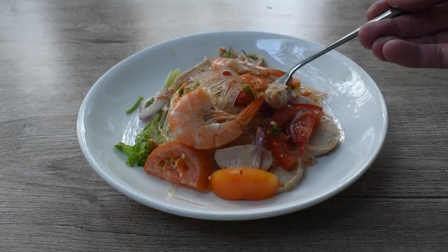 glass noodle with shrimp and minced pork spicy salad on plate stabbing by silver fork