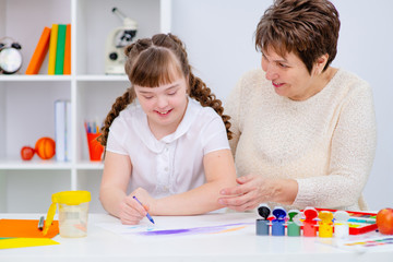Mom deals with a girl with Down syndrome. The concept of home schooling and classes. Mother and daughter play together