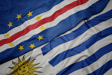 waving colorful flag of uruguay and national flag of cape verde.