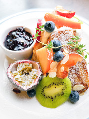 Delicious sweets French toasts with vanilla yogurt, blueberries jam and fresh fruits for a vitamin breakfast.