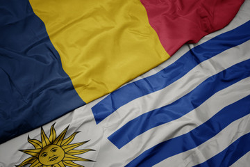 waving colorful flag of uruguay and national flag of chad.
