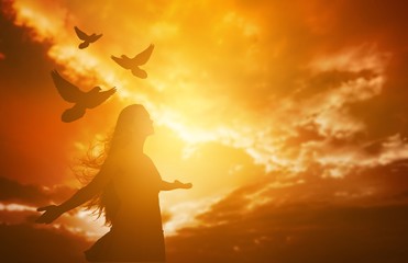 Silhouette of young woman and free birds fly