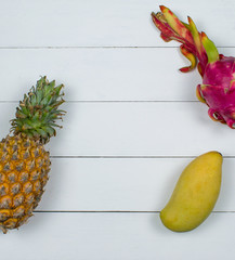 Exotic asia fruits on white wood background. Assorted tropical summer fruits. Mango, dragon fruit,...
